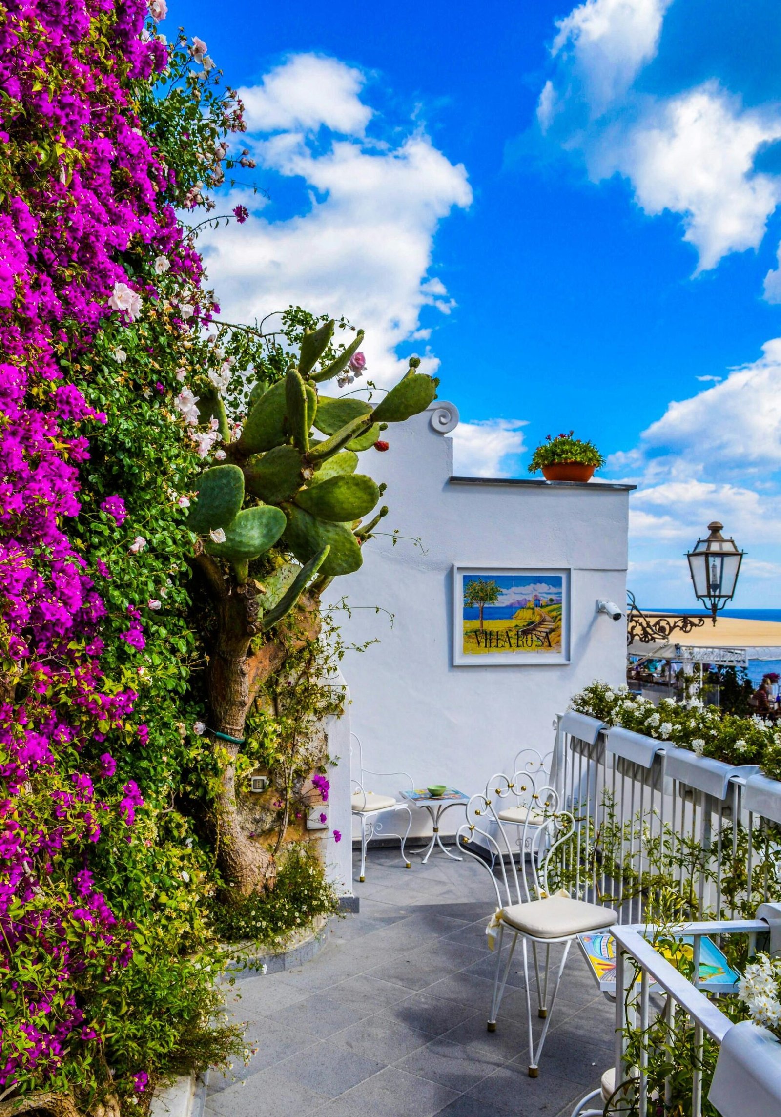 Charming Mediterranean balcony adorned with vibrant bougainvillea, overlooking sea.